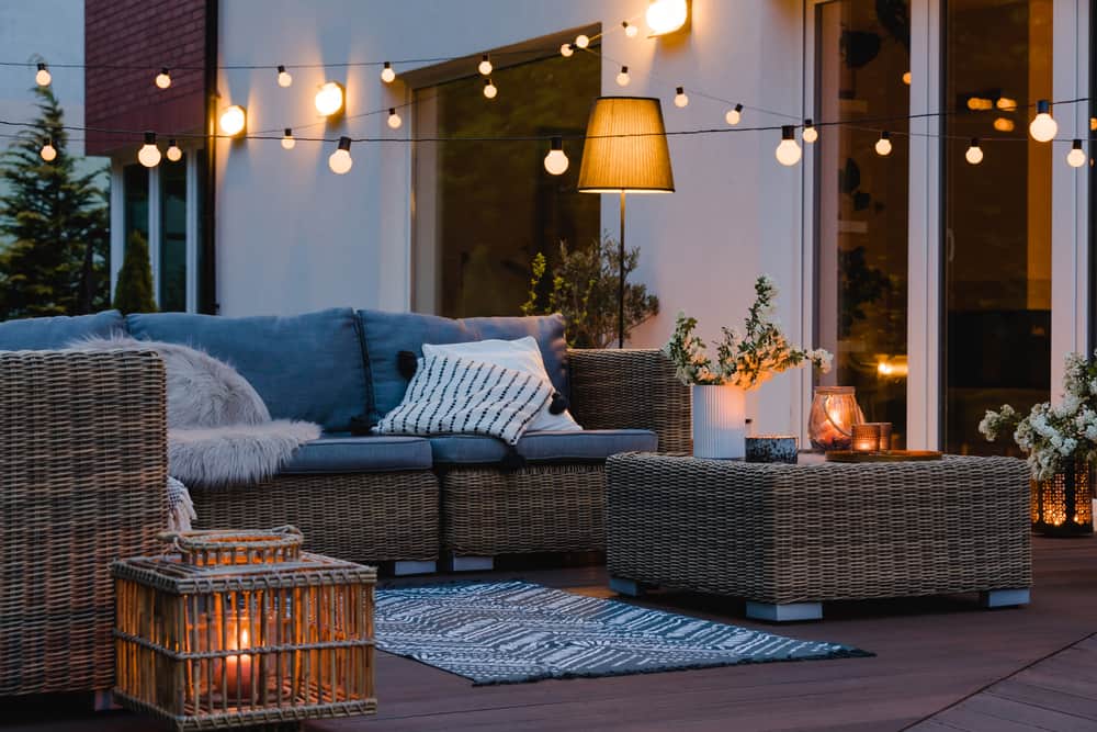 So sorgen Sie für Wohlfühlathmosphäre auf Ihrer Terrasse: mit einer stimmungsvollen Beleuchtung auf Ihrer Terrasse. Eine schön dekorierte Terrasse mit Kerzen, Lichterketten und einer Lampe, verschiedene Lichtquellen.